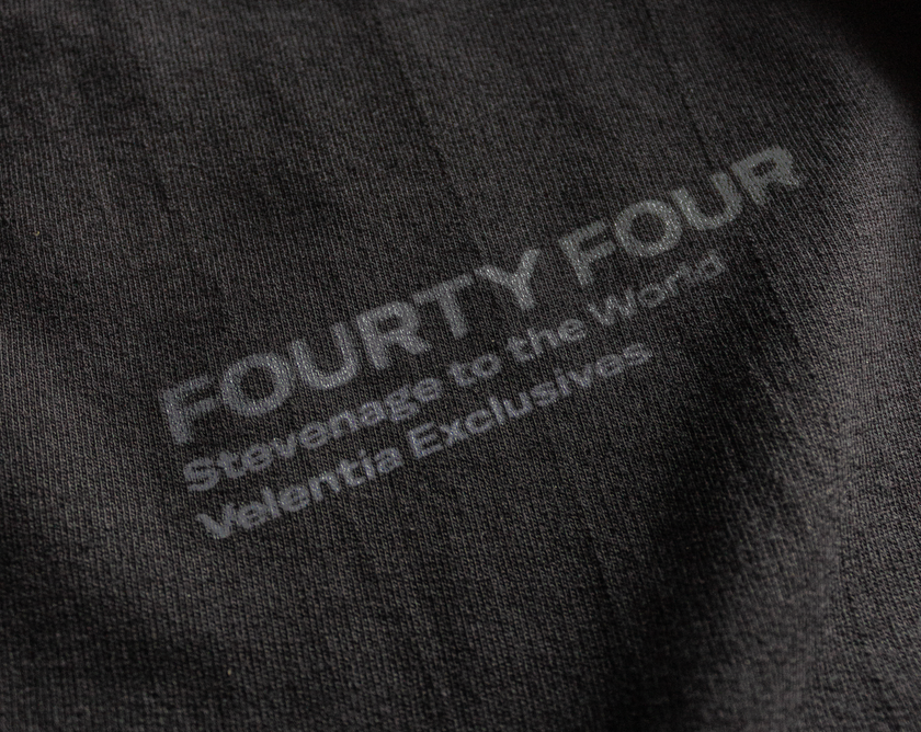 Close-up of Velentia black Tokyo T-shirt showing detailed motorsport inspired text graphic screen print